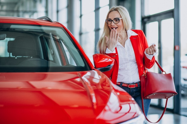 Bedrijfsvrouw die auto zoeken mobiel bij een autoshowroom