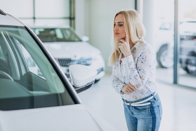 Bedrijfsvrouw die auto zoeken mobiel bij een autoshowroom