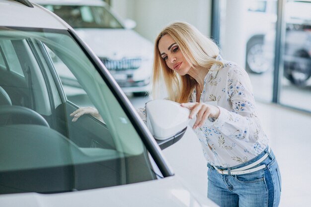 Bedrijfsvrouw die auto zoeken mobiel bij een autoshowroom