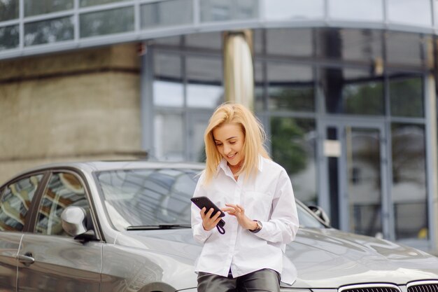 Bedrijfsvrouw die de slimme telefoon buiten bureaucentrum met behulp van