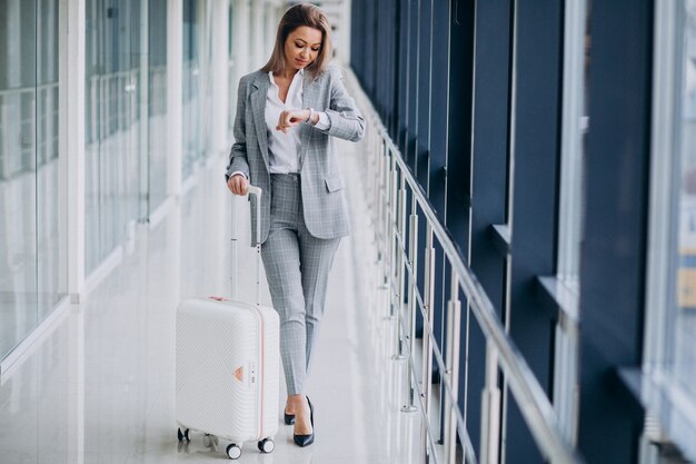 Bedrijfsvrouw die met reiszak in luchthaven op een vlucht wachten