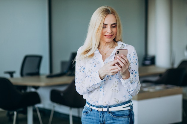 Bedrijfsvrouw in bureau die telefoon met behulp van