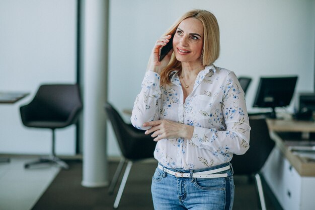 Bedrijfsvrouw in bureau die telefoon met behulp van