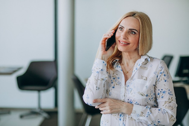 Bedrijfsvrouw in bureau die telefoon met behulp van