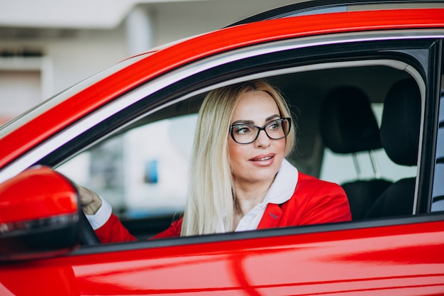 Bedrijfsvrouwenzitting in een nieuwe auto in een autotoonzaal