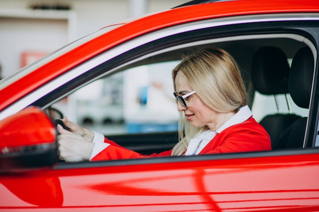 Bedrijfsvrouwenzitting in een nieuwe auto in een autotoonzaal