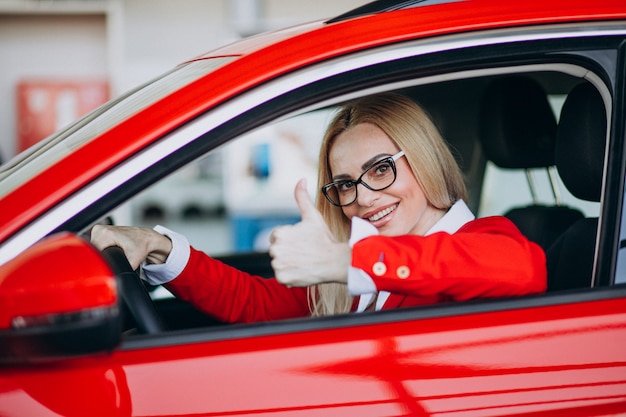 Bedrijfsvrouwenzitting in een nieuwe auto in een autotoonzaal