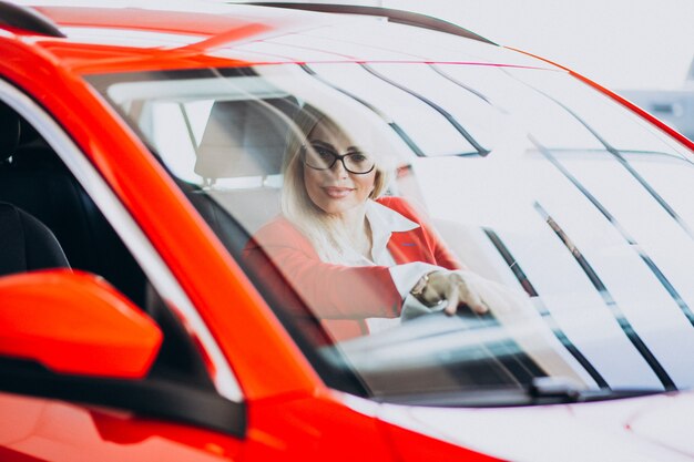 Bedrijfsvrouwenzitting in een nieuwe auto in een autotoonzaal