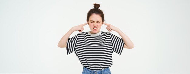 Gratis foto beeld van een geïrriteerde vrouw die haar oren sluit. ze kan het geluid niet verdragen. ze wordt gestoord door luide muziek.