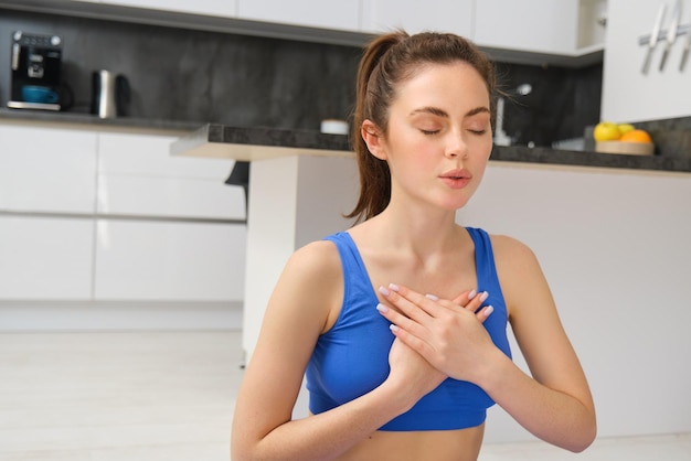 Gratis foto beeld van een rustige en ontspannen vrouw die mediteert en ademhalingsoefeningen doet terwijl ze de handen op de borst houdt