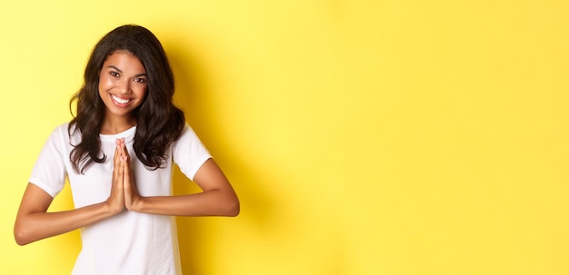 Gratis foto beeld van een schattige afro-amerikaanse vrouw die dank u zegt en glimlachende pershanden samen om gr uit te drukken