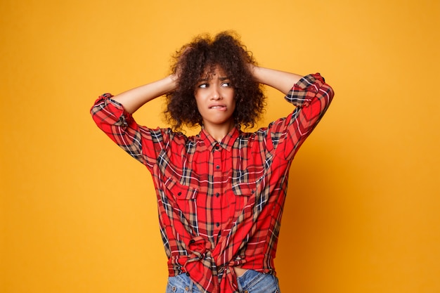 Gratis foto beeld van het emotionele jonge afrikaanse vrouw stellen geïsoleerd over oranje achtergrond. verras gezicht. studio-opname.