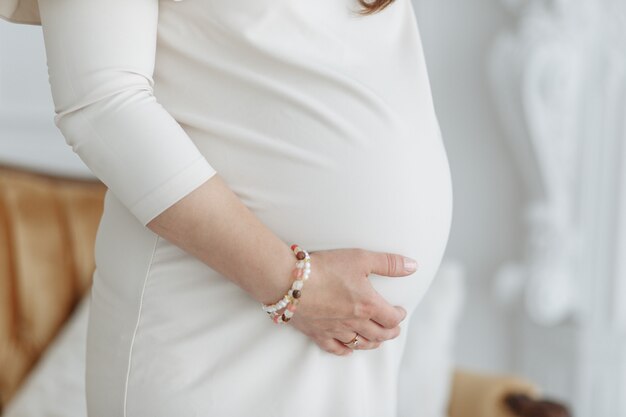 Beeld van zwangere vrouw wat betreft haar buik met handen.