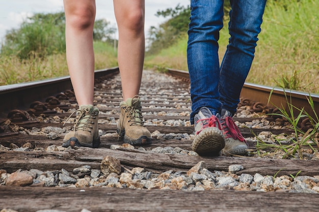 Gratis foto beenaanzicht van het paar dat op treinsporen loopt