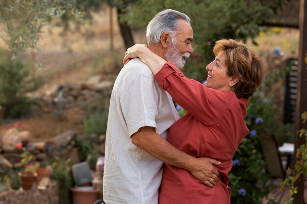 Bejaard stel dat elkaar romantisch vasthoudt in hun tuin op het platteland