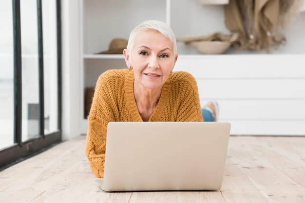 Bejaarde die met laptop glimlacht