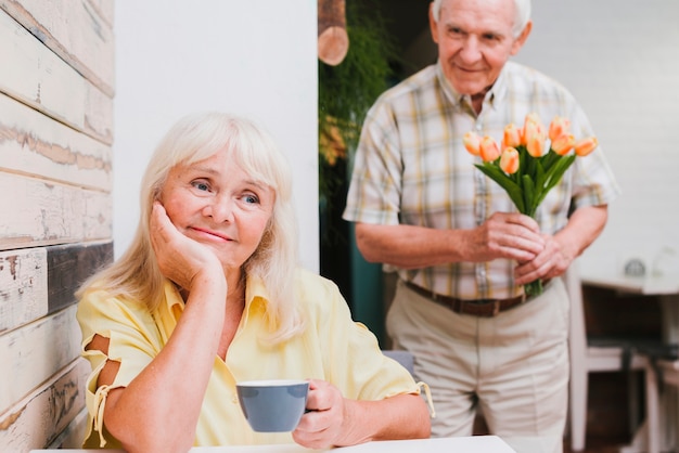 Bejaarde die zich achter geliefd met bloemen bevindt