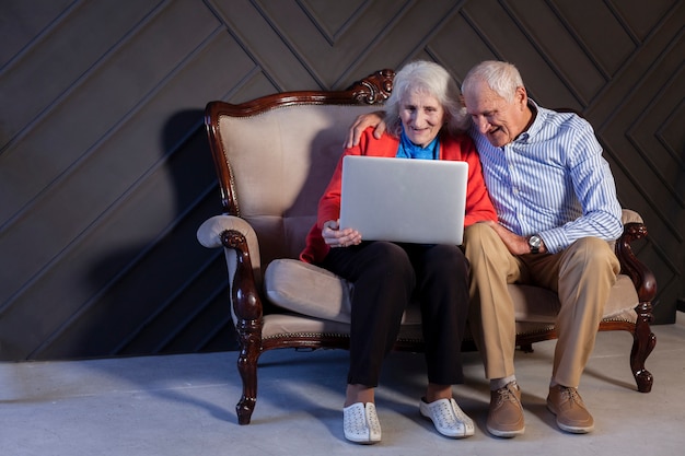 Bejaarde en vrouw die laptop met behulp van