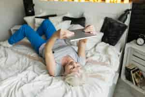 Gratis foto bejaarde met tablet op bed