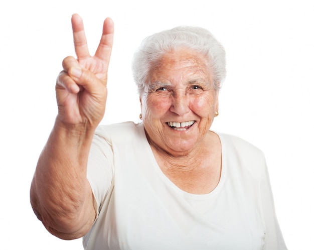 Bejaarde vrouw glimlachend met twee verhoogde vingers