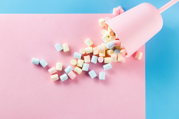 Beker gevuld met marshmallows op roze papieren oppervlak