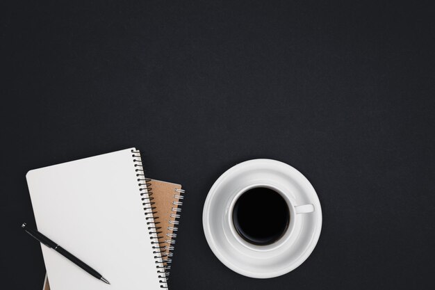 Beker koffie en notitieblokken op een zwarte achtergrond
