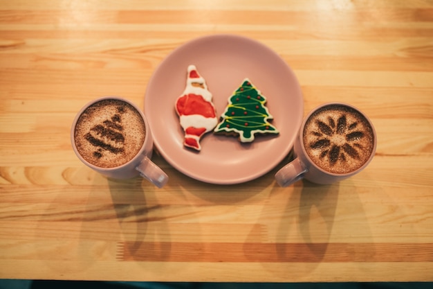 Bekers met koffiestandaard aan beide zijden van bord met kerstmisbroodjes