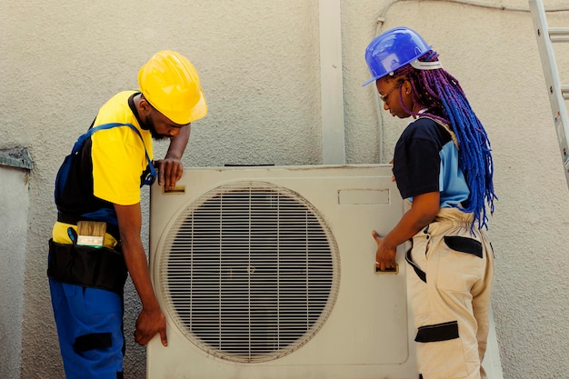 Bekwame elektricien en nauwkeurige monteur die de oude defecte condensor opent om deze te vervangen door een nieuw performant hvac-systeem voor buiten, nadat de freontank is leeggemaakt en de compressor is vervangen