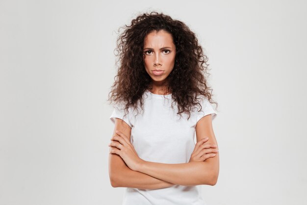 Beledigd krullende vrouw kijken naar de camera met gekruiste armen