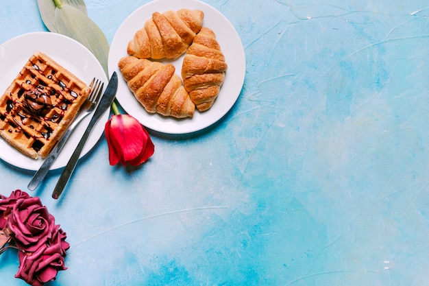 Gratis foto belgische wafel met croissants en bloemen