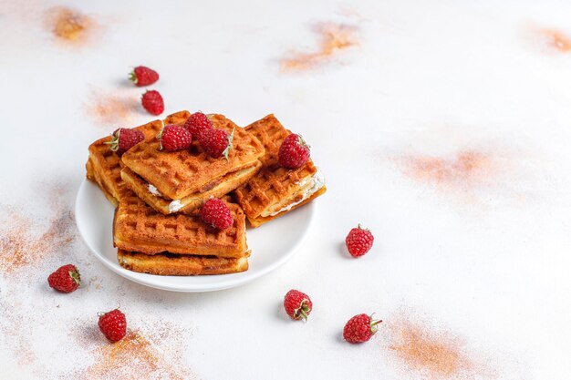 Belgische wafels met room en verse frambozen.