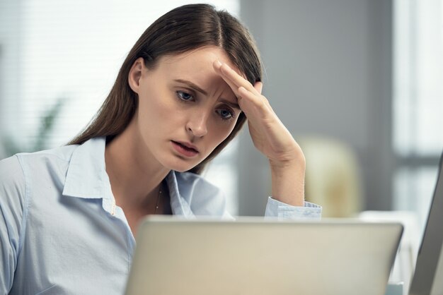 Benadrukt blanke vrouw zitten in kantoor voor laptop