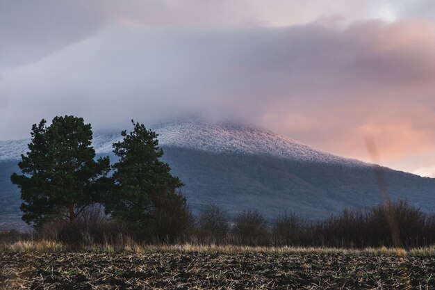 Berg bedekt met sneeuw en een bewolkte hemel tijdens de zonsondergang