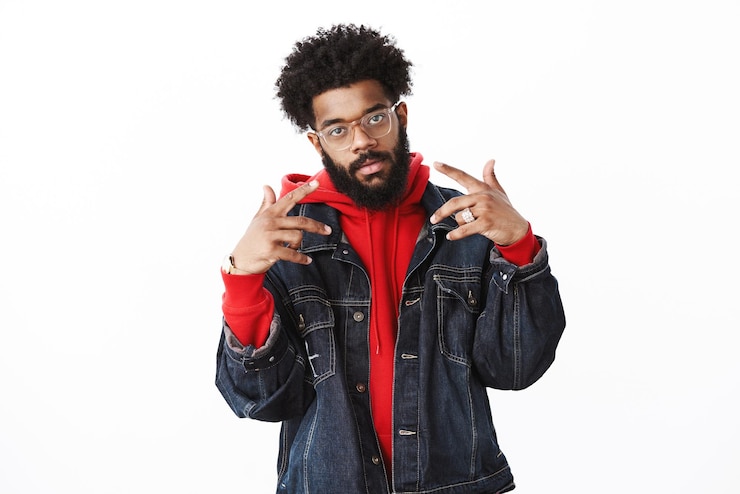 Gratis Foto beroemdheid poseren paparazzi zelfvoldane coole en arrogante afro-amerikaanse bebaarde mannelijke rapper met afro kapsel met v-tekens of yo gebaar als stijlvol en zelfverzekerd poseren over grijze muur