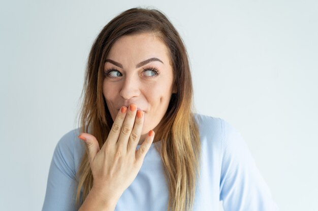 Beschaamd mooie vrouw die de mond bedekt en opzij kijkt.