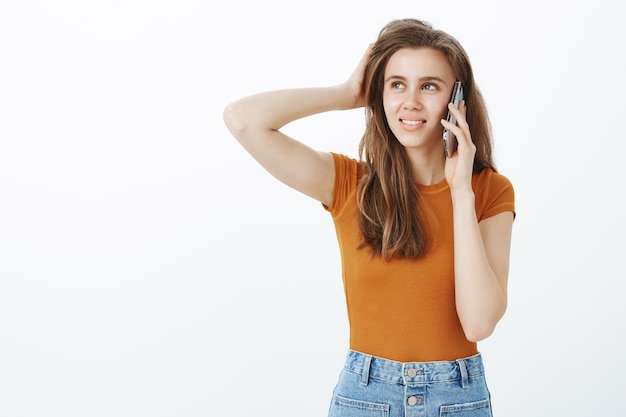 Besluiteloos schattig meisje praten over de telefoon en besluit nemen, denken en opzoeken