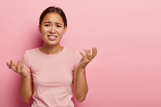 Besluiteloze, ontevreden, onwetende vrouw fronst haar wenkbrauwen en gebaart met twijfel, verward in moeilijke situatie, kan geen beslissing vinden, klemt zijn tanden op elkaar, ziet er ongelukkig uit, draagt vrijetijdskleding