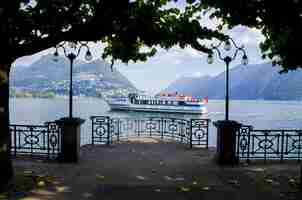 Gratis foto betoverend beeld van een zeilschip tegen mistige bergen in lugano, zwitserland