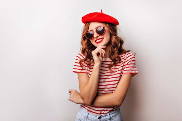 Bevallig kaukasisch meisje met gemberhaar het glimlachen. prachtige jonge dame in rode baret genieten van fotoshoot.