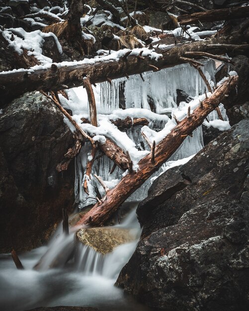 Bevroren waterval in het bos met omgevallen bomen en ijsstalactieten geschoten bij lange blootstelling