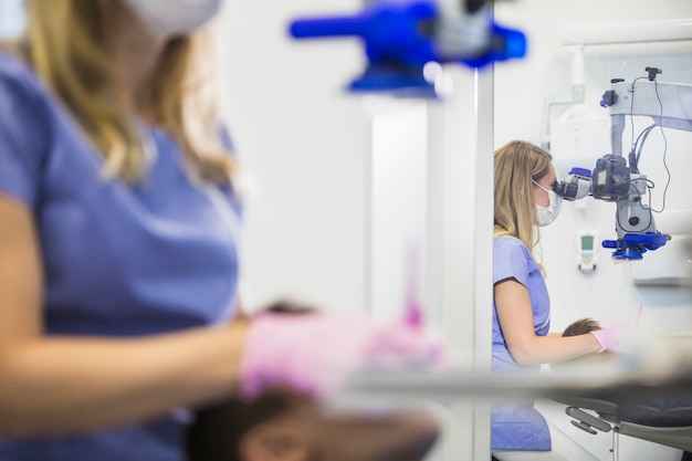 Bezinning van een vrouwelijke tandarts die door microscoop in spiegel kijkt