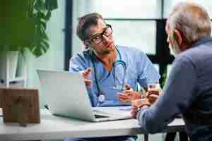 Gratis foto bezorgde arts die laptop gebruikt en gezondheidsproblemen oplost met zijn volwassen patiënt tijdens medische afspraak