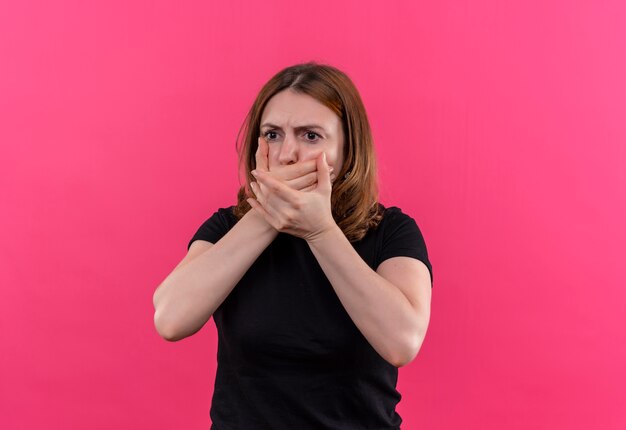 Bezorgde jonge casual vrouw met handen op mond op geïsoleerde roze ruimte met kopie ruimte