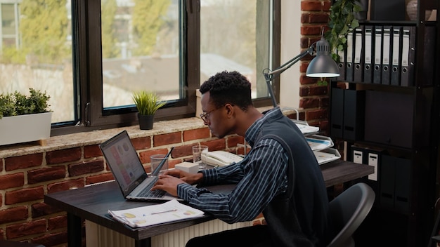 Gratis foto bezorgde persoon die onder druk financieel papierwerk doet, zich gestrest en wanhopig voelt. afro-amerikaanse man slaagt er niet in om voor de deadline aan een businessplan te werken, depressief over mislukking