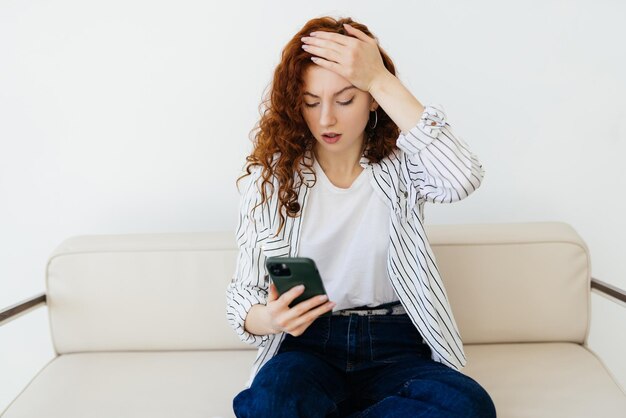 Bezorgde vrouw die thuis op de bank zit en een negatief telefoongesprek heeft, slecht nieuws hoort of ruzie maakt