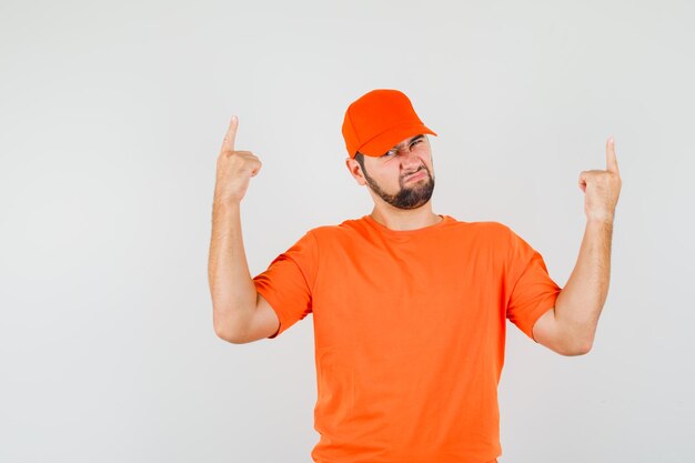 Gratis foto bezorger in oranje t-shirt, pet naar boven gericht en hopeloos, vooraanzicht.