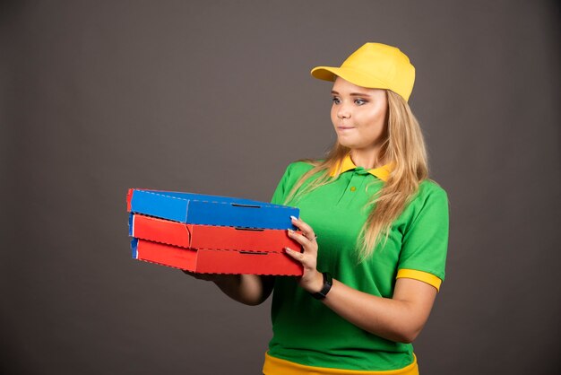 Bezorger in uniform met kartonnen pizza.