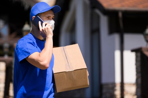 Gratis foto bezorger met gezichtsmasker met pakket