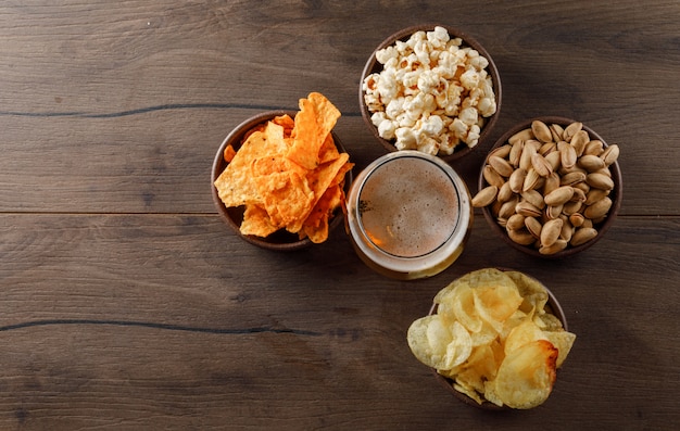 Bier in een beker glas met snack bovenaanzicht op een houten tafel