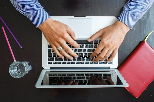 Bijgesneden afbeelding van een jonge man aan het werk op zijn laptop thuis bovenaanzicht van zakenman handen bezig met laptop op kantoor